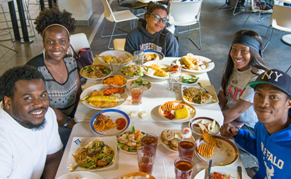 Female and male students sitting at a table at Crossroads Culinary Center (C3) with a lot of plates full of food during a lobster night event.